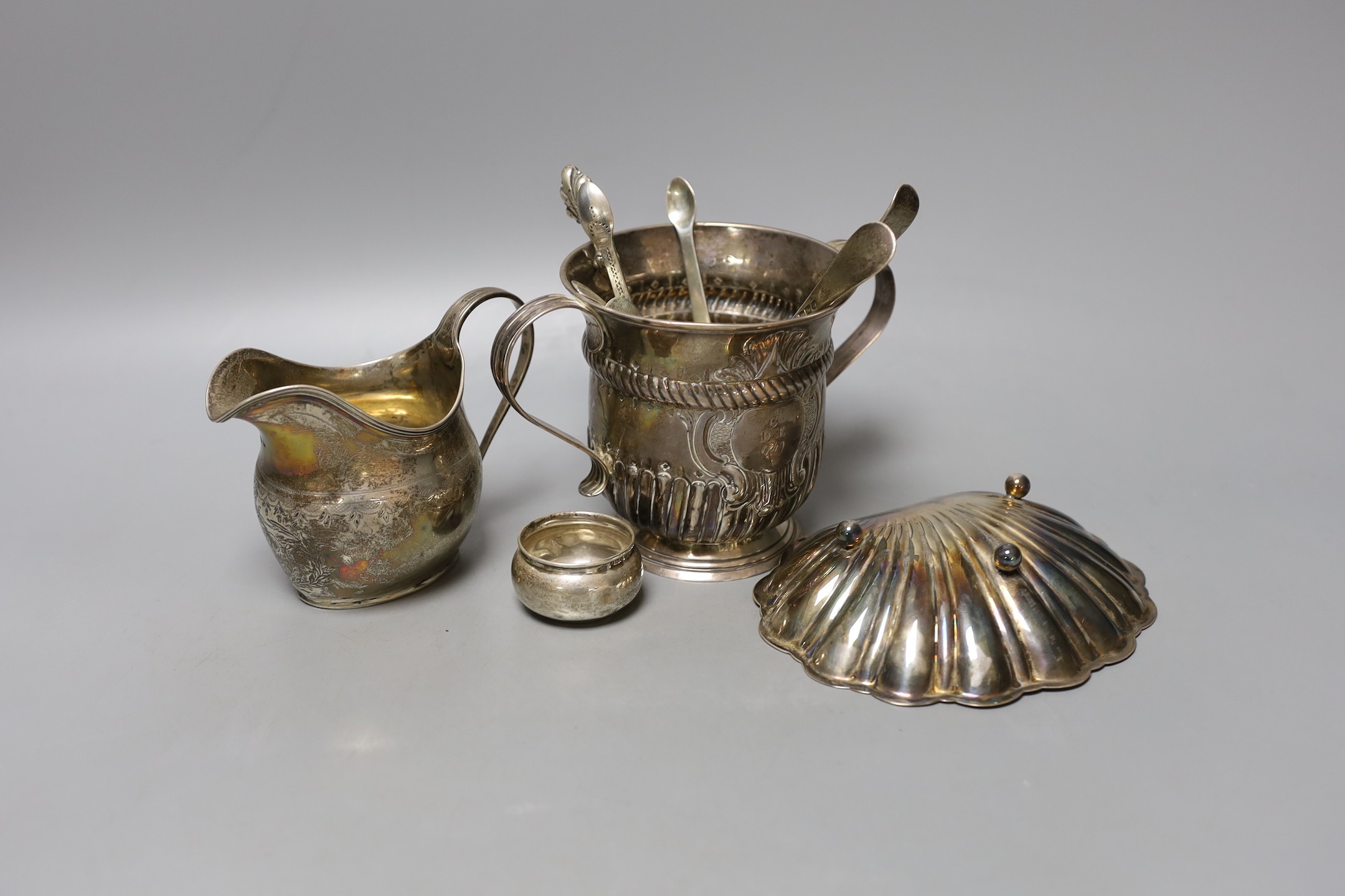 A George II silver porringer, London, 1748, 10.9cm, a George III silver cream jug, a silver shell dish, pair of silver tub salts, four items of silver flatware and two other items.